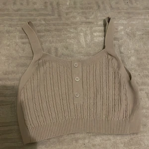 Croppad topp - Toppen har används 1 gång och beige. Materialet är mjukt. Toppen är i storlek xs och är croppad