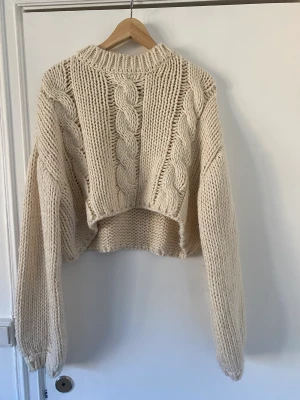 Stickad Tröja, NA-KD - Beige kabelstickad tröja från NA-KD i lite kortare modell. Endast använd två gånger och i mycket fint skick. 