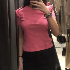 Rosa t-shirt - Säljer en rosa tröja med volanger på ärmarna. Använt ca två gånger och tror verkligen den passar till ett par lågmidjade jeans. Från Zara och köpt för en månad sedan.