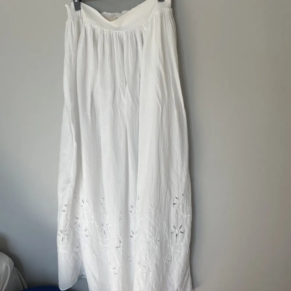 Lång vit kjol med broderi detaljer längs ner🤍Passar storlek 34-38. Kjolar.