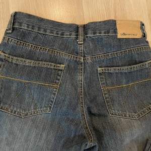 Mörk blåa jeans med detaljer som är mid waist 