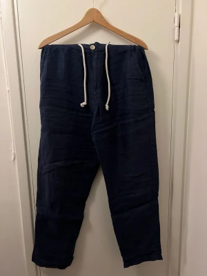 Marinblå linnebyxa med snören - Ett par marinblå linnebyxor med både snörning och gylf. Byxorna är från Zara och är i storlek 38 (M/L)