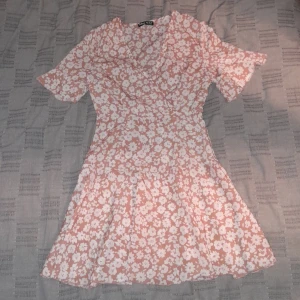 Blommig klänning - Klänningen är 117 cm lång och är i ett utmärkt skick! Framsidan liknar en omlott men varan har en dragkedja istället för band. 