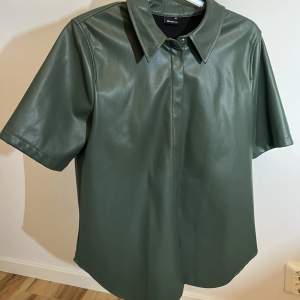 Cool kortärmad skjorta i grön färg från Gina Tricot. Är i läderimitation ✨ storlek M 