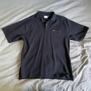 Svart Piké - Yôke - Köpt hos Junkyard.com och endast testad använd en gång. Skick 10/10 och sitter avslappnat.