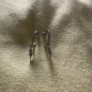 Silvriga örhängen  - Silvriga örhängen ifrån na-kd. Halvring med en blixt på. Lite små ”diamanter” på. 