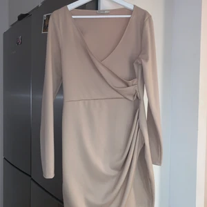 Festklänning  - Beige klänning från Nelly i strl L. Passar även en M. Använd 1 gång. Sitter jättefint på kroppen och väldigt bra längd, ungefär till knäskålarna. 