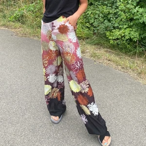 Kostymbyxor - Sjukt coola utsvängda byxor med blommönster, i ett silkes matrial. Säljes billigt pga knottriga. 