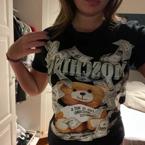 Grön moschino tröja - Fake t shirt som jag köpte för 400 men nästan aldrig använt. I bra skick med en lapp i nacken som det står moschino på! Kan skicka bild på lappen också