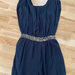 Mango byxdress. Korta ben. Strl S - Mycket fin byxdress.Grå, Skirt material paljetter i midjan. Öppen rygg. Aldrig använd. Storlek S. Köparen betalar frakten, betalning med swish. 