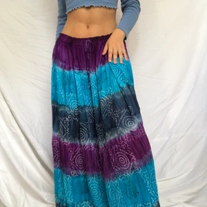 Bohemisk kjol - Bohemisk flerfärgad kjol med vita spiraler på framsidan. Tiedyeliknande växling mellan färgerna. Kan lossas och dras åt i midjan med snöring. Gott second hand skick. Kan bäras både hög och lågmidjad. Når ner till anklarna på mig som är 169 och bär M/L i byxor 