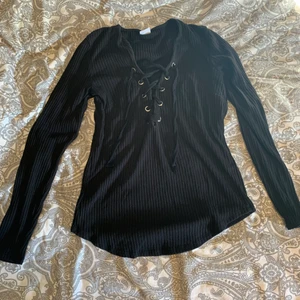 Tröja - Svart tröja med snörning från ginatricot. Storlek L, men skulle kunna tänka mig att den även passar en M. Ribbad, och ganska mjukt material. Säljes pga att den är för stor.