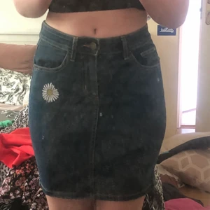 Jeanskjol - En kort, blå jeanskjol. Kjolen är väldigt stretchig. Den är en broderad blomma på sidan. 