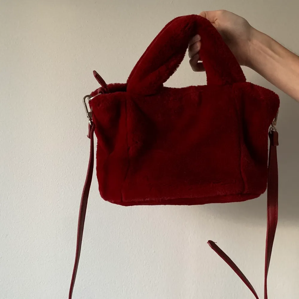 En röd supermjuk ”päls”-väska från Bershka. Den har en avtagbar justerbar rem och stängs med en fungerande dragkedja. Använd endast ett fåtalgånger så är som i nyskick. FRAKT tillkommer från 66kr. . Väskor.