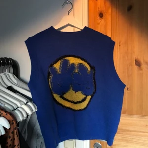 Cool blå väst med smiley på - Aldrig använt, inte riktigt västtypen tyvärr.. men den är så cool! Frakt betalar köparen själv :) minns ej nypris men gissar på 200