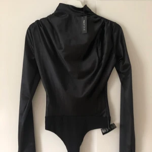 Svart siden body - En svart body i siden tyg. Aldrig använd. Storlek xs.