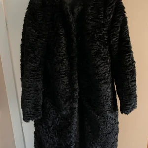 Svart kappa i fake päls - Snygg kappa i fake päls från H&M. Använd vid få tillfällen. Är i storlek 38. Kappan har fickor. Väldigt snygg med ett bälte i midjan. 