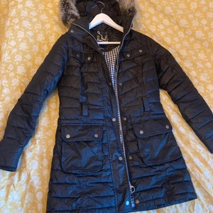 Barbour International vinterkappa - Barbour International vinterkappa med avtagbar huva (faux fur). Supervarm och sitter galet snyggt! Möjligt att bära med skärp, men saknas eftersom jag tyckte det var bättre utan. Knappt använd. Nypris cirka 5000