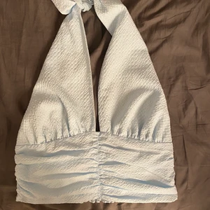 ljusblå halterneck - Ljusblå halterneck, kan äbdra storleken i halsen beroende på hur tajt man vill att den ska sitta, enbart provad så helt ny. från gina tricot, men slutsåld. storlek 40 men kan göras mindre samt större då man kan reglera den❤️