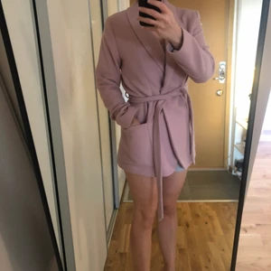 Kort kappa från MQ - Jättefin kort kappa/kavaj-jacka i ljus rosa. Ullblandning. Från MQ. Storlek 34. Endast använd ett fåtal gånger, fint skick. Köparen står för frakt.