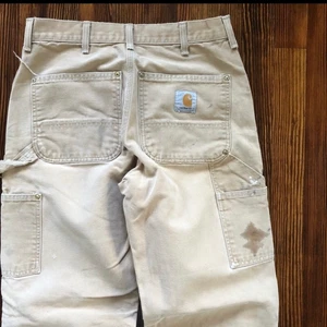 Carhartt Double Knee Pants - Beiga vintage double knee pants från Carhartt i st 31x32. (Midja 31, längd 32) En del slitningar samt stains som visat på bilderna, vilket förstärker den snygga vintage stilen. Inga hål! Billigare vid snabb affär