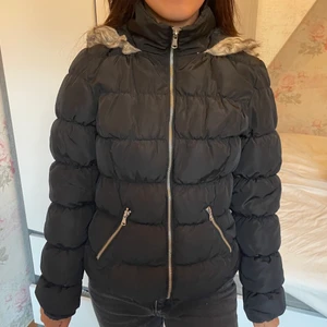 Vinterjacka - En svart vinterjacka i 100% polyester. Från H&Ms ”Divided” i strl 34. I använt skick men har inga defekter förutom ”pälsen” på luvan som blivit slitet i tvätten (se bild nr 2)