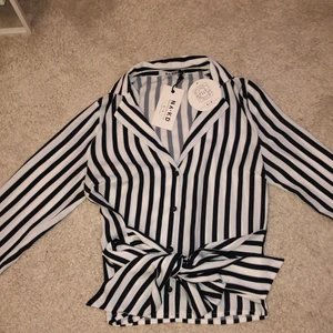 Randig skjorta bunden i midjan  - Helt ny, säljs pga liten storlek. Färg: randig🤍 köpt från NA-KD