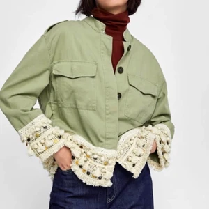 Kort jacka - Zara - Kort grön jacka/parkas med tofsar i strl S. Slutsåld på Zaras hemsida. Köpt för 499kr. ‼️HELT NY‼️ med tillhörande extraknapp (se tredje bild). Säljer då den inte har kommit till användning. Fraktkostnad tillkommer. ⚠️De två första bilderna är tagna från Zaras hemsida⚠️