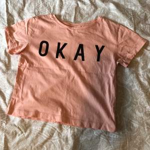 Rösa t-shirt med text ”OKAY”. Väldigt bra skick då den knappt är använd.