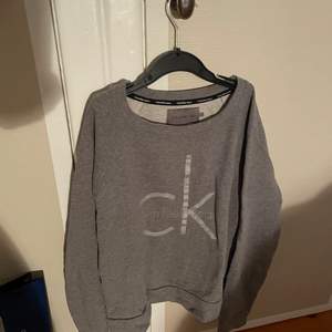 En grå tröja från Calvin klein köpt på en outlet i Spanien.