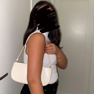 Väska  - Axelväska i beige där det står nakd litet på väskan 