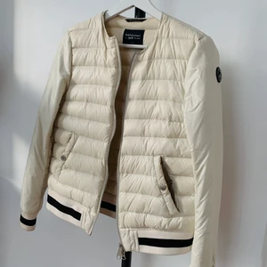 Vårjacka Peak Performance  - Vit vårjacka i dun från peak performance storlek S. Någon fläck längst ner på ärmarna som jag ej vet om de går bort i tvätt. Därav priset!