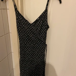 Svart klänning - Svart klänning med mönster och snörning vid midjan. Köpt på hm i storlek s men passar även xs