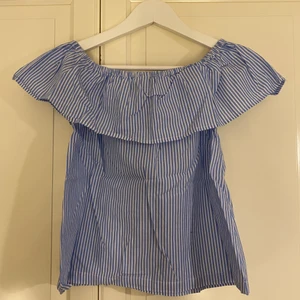 Blus - Blå- och vitrandig blus med off-shoulder, men som även går att ha som en vanlig tröja på axlarna. 
