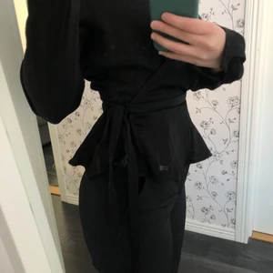 Nelly svart topp/blus - Svart topp/blus från NLY Trend i strl 34. Spänne finns tillgängligt vid bröst. Använd fåtal gånger, i bra skick! Köparen står för frakt. Bäst bud!