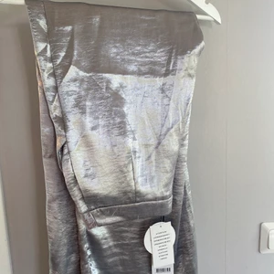 Silvriga vida byxor, storlek 38 - Jättecoola silvriga byxor med hög midja och vida ben. Helt oanvönda, lappar kvar. Perfekt till nyår! Storlek 38, men skulle säga att det passar en 36 också.