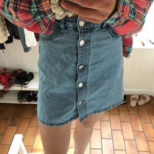 Jeanskjol med knappar - Hyfsat ljus jeansfärg. Går att ha skärp i. Knappar hela vägen uppifrån och ner. Köpare står för frakt.