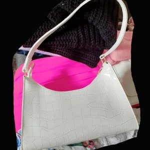 Vit väska - Vit mönstrad väska i glansigt material från JFR💗Superfint skick då den är oanvänd. Säljes pga att den inte kommit till användning. Frakt: 66:- spårbart 