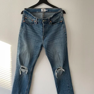 Blå straight jeans med hål - Ett par blå jeans med hål vid knäna från Lager 157. Jeansen straight och i storlek M så de passar ifall man är ungefär 177 till 187. Priset är 100 kr.