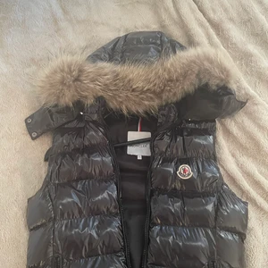 Moncler väst  - Moncler väst med luva med äkta päls. Storlek xs passar även s. Luvan går att ta av 