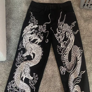 Jeans - Säljer ett par svarta jeans med motiv av drakar. Minns inte vart jag köpt dessa. Storlek 38 och passar mig som är 161 lång samt väger 57 kg 😊 Kan skicka på posten, köparen kan hämta i Vallentuna, alternativt mötas upp någonstans centralt i Stockholm ✨