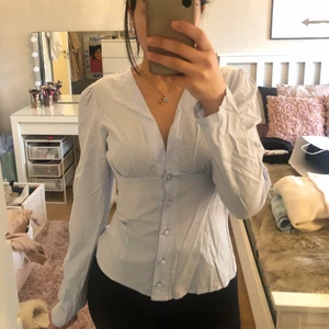 Topp från NAKD - En helt oanvänd topp/skjortblus? från NAKD, i storlek 34. Den är i en ljusblå färg med en fin v-ringning.