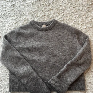 Ulltröja H&M - En ulltröja från hm i en beige/grå färg och slits i ärmar som går att vika upp. Strl L. Nypris 500kr