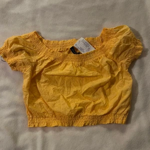 Gul sommartorp  - En fin gul sommartopp som är croppad! Off shoulder med reså upptill. Litet blommönster på, se bild 3! 💛 Aldrig använd, lapp kvar! Köpt för 149kr.