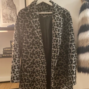 Kappa  - Säljer fin kappa i leoprint, svart/grå. Kan HÄMTAS i Trollhättan eller skickas mot frakt. Kappan går över knäna på mig som är 174cm lång. 