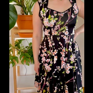 Blommig klänning  - Svart blommig klänning av stretchigt material. Aldrig använd.