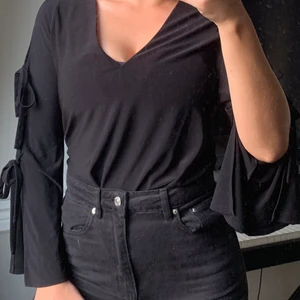 Svart Knutblus strl 38-40 - En blus från River Island med knutar i armarna. Fint skick! Storlek 10. (38-40)