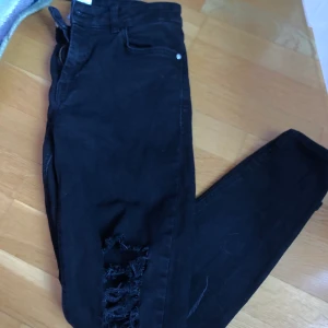 Svarta ripped jeans  - Svarta ripped jeans från mango i storlek 38, säljs pga ingen användning :(. Har lite veck längst ner (de sista bild) och har några vita ish färg fläckar (se 1a bild) därav priset. Annars i väldigt bra skick och är super fina!! Nypris: 249kr Pris: 90kr. Kan fraktas men du står för frakt!!🥰