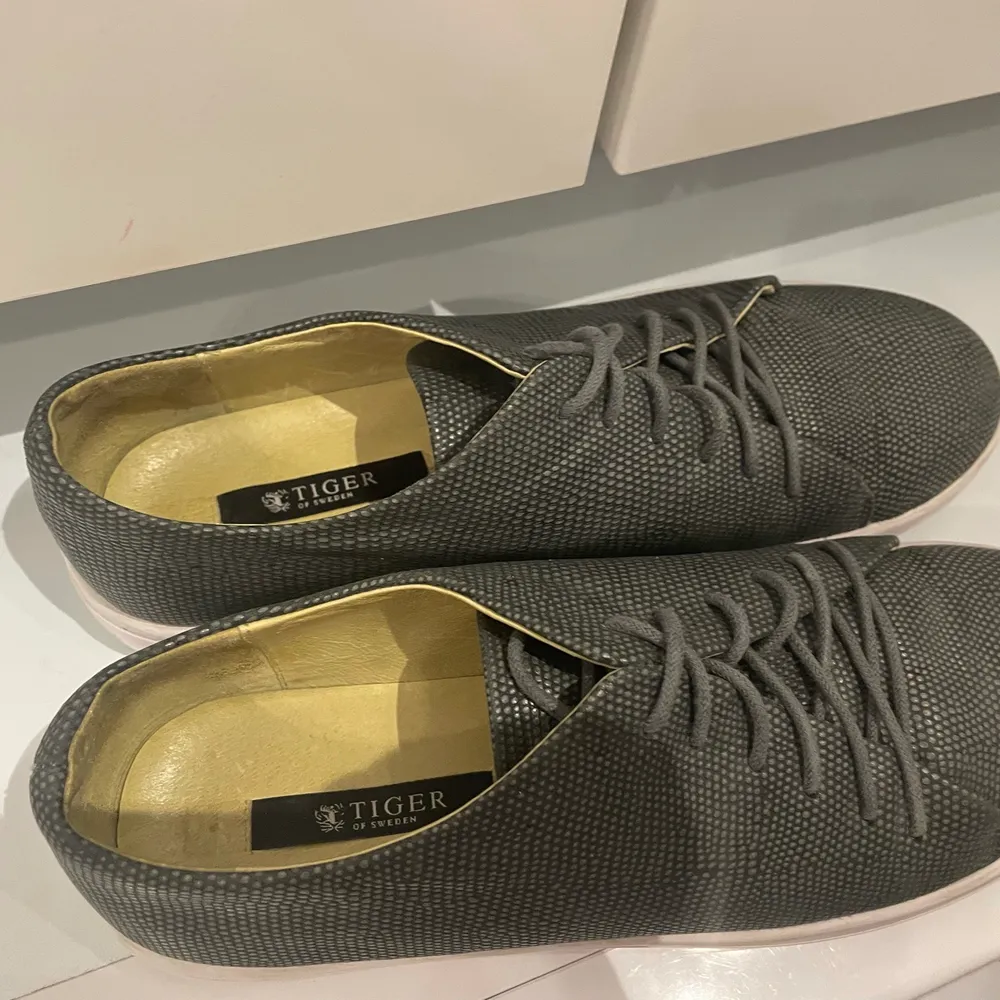 Sparsamt använda sneakers från Tiger of Sweden.  Storlek 40 men passar mig som har 39. Nypris 1499kr.  Grått skinn med ormeffekt och hög vit sula.. Skor.