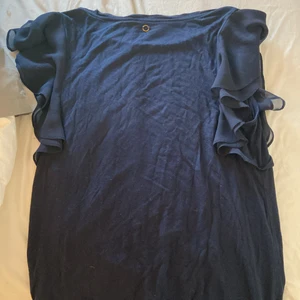 Vet inte riktigt vart den är ifrån - En blå topp i storlek S med volang på ärmarna 